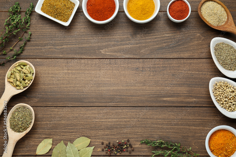 Many different spices on wooden table, flat lay. Space for text