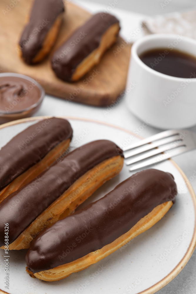 Delicious eclairs covered with chocolate on grey table, closeup Delicious eclairs covered with chocolate on grey table, closeup