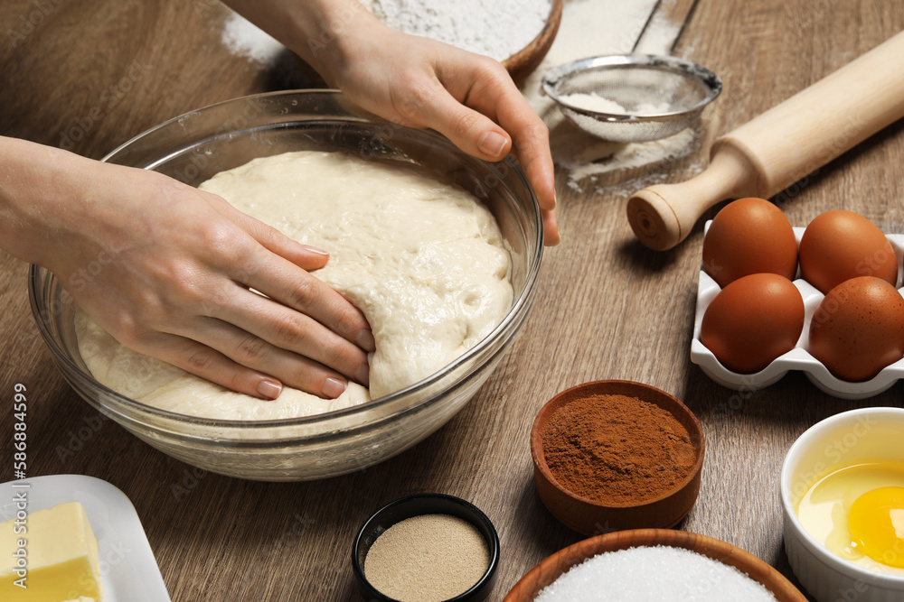 Fototapeta premium Woman kneading yeast dough for cake at wooden table, closeup