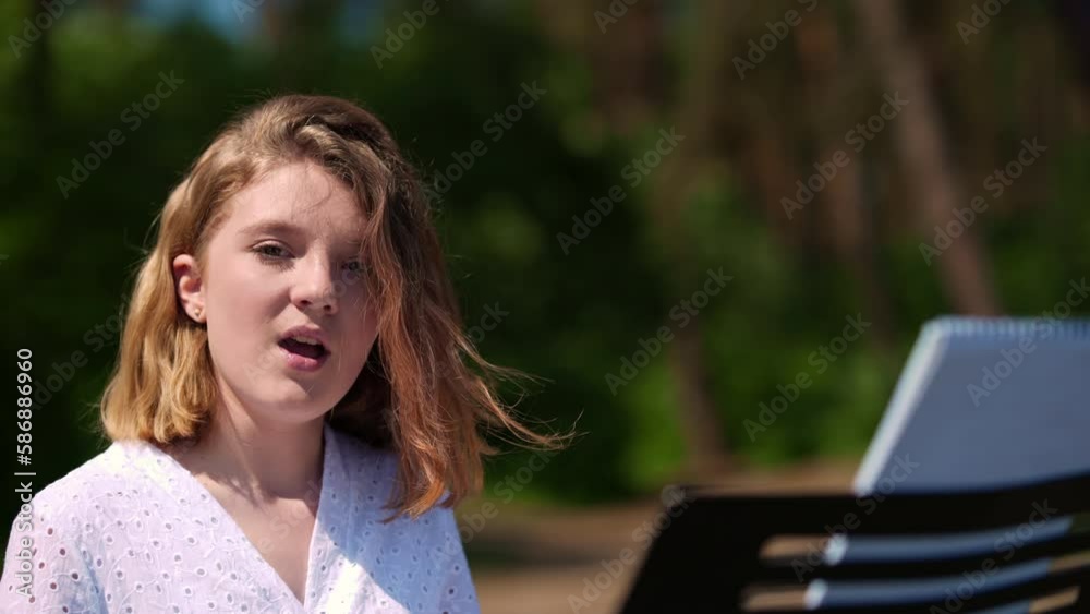 Portrait of charming talented teenage girl on the left singing looking at camera outdoors. Adolescent Caucasian teen singer posing playing piano synthesizer performing in forest on sunny day Portrait of charming talented teenage girl on the left singing looking at camera outdoors. Adolescent Caucasian teen singer posing playing piano synthesizer performing in forest on sunny day