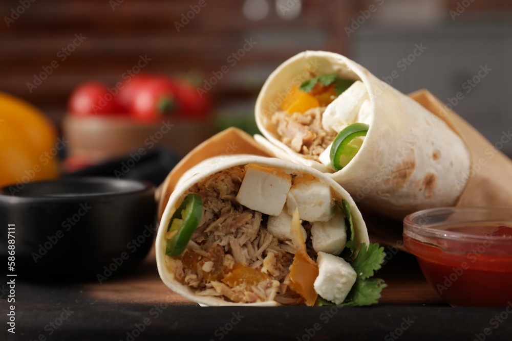Delicious tortilla wraps with tuna, cheese, vegetables and sauce on table, closeup Delicious tortilla wraps with tuna, cheese, vegetables and sauce on table, closeup
