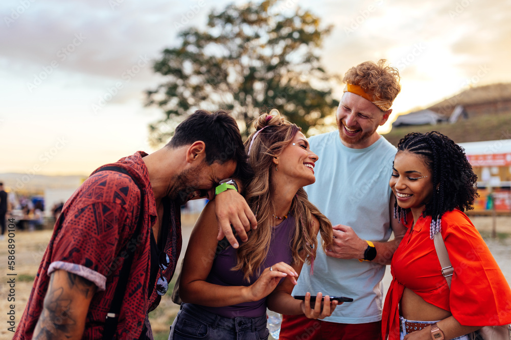 Obraz premium Friends looking up concerts on cellphone at music festival.