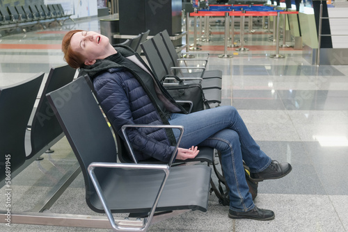 Woman sleeps with her mouth open in the departure area of an international airport. The flight passenger overslept the departure time.