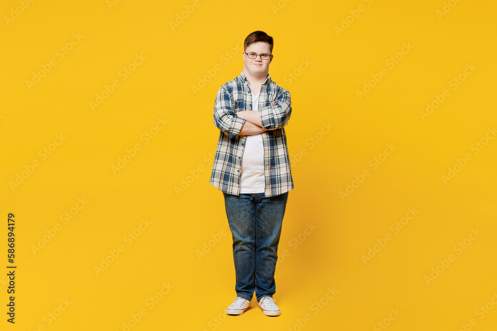 Fototapeta premium Full body young smiling man with down syndrome wears glasses casual clothes look camera hold hands crossed folded isolated on pastel plain yellow color background. Genetic disease world day concept.
