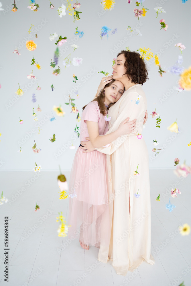 portrait of mother and daughter against the background of soaring flowers