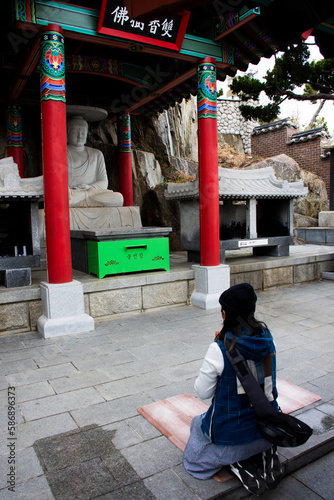 Traveler thai women travel visit and respect praying blessing wish holy mystery ancient stone buddha in Haedong Yonggungsa temple at Gijang on February 18, 2023 in Busan or Pusan or Pusan, South Korea photo