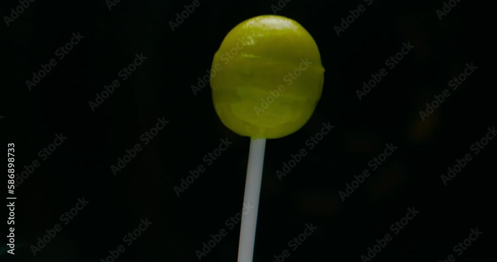 Candy with green stick rotating, lollypop in black background and deforming for visual effect.