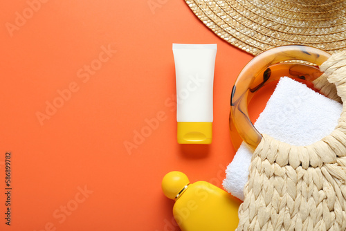 Bilde på lerret Suntan products, straw hat and bag on orange background, flat lay