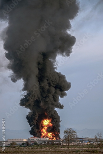 Chemical solvent plant burns down with a black column of toxic smoke.
