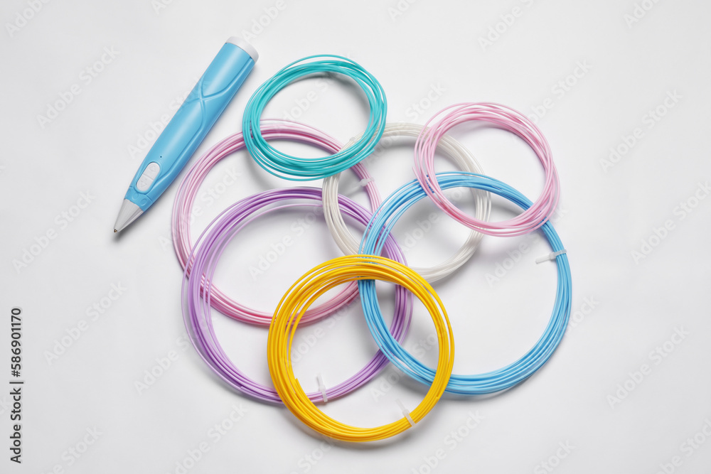 Fototapeta premium Stylish 3D pen and colorful plastic filaments on white background, flat lay