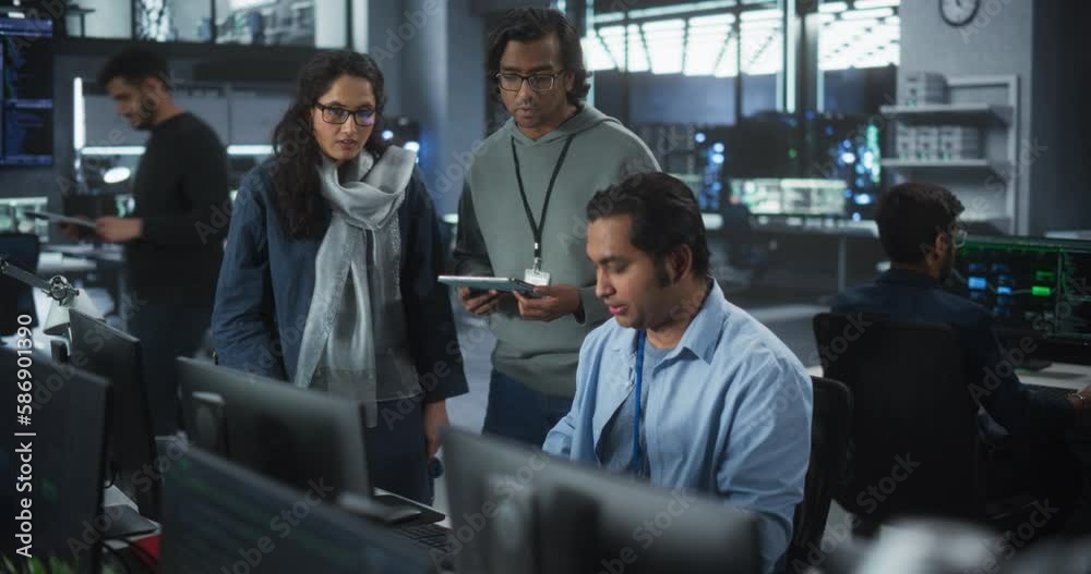 Focus Switching from Desktop Computer Display with Software Code to a Team of Three Talented Young Indian Developers Discussing a Technological Project in Modern Industrial Office