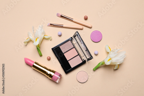 Flat lay composition with different makeup products and beautiful flowers on beige background