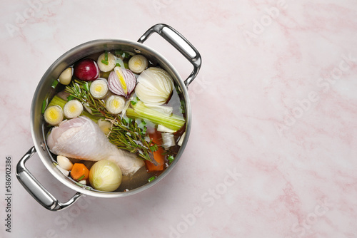 Different ingredients for cooking tasty bouillon in pot on pink marble table, top view. Space for text