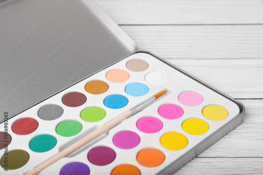 Watercolor palette with brush on white wooden table, closeup Watercolor palette with brush on white wooden table, closeup
