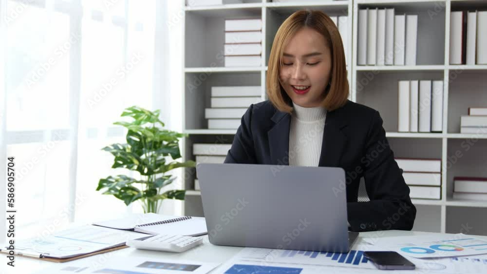 Young Asian business woman employee or executive manager using computer looking at laptop and talking leading hybrid conference remote video call virtual meeting or online training working in office. Young Asian business woman employee or executive manager using computer looking at laptop and talking leading hybrid conference remote video call virtual meeting or online training working in office.