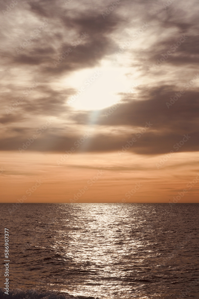 Seascape with beautiful sunlight at sunrise. Sunbeams reflecting blue sea orange sky with space for text.