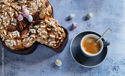 Colomba pastries, a cup of espresso coffee and chocolate colored quail eggs on a stone table. Italian traditional food with hard shadows