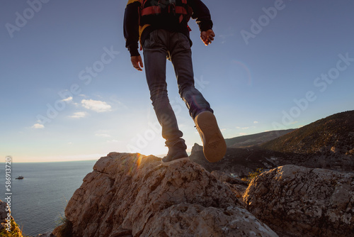 Sporty man hiker walks at sunset with backpack