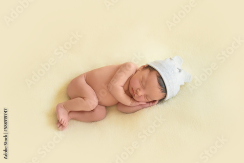 Newborn baby infant with dark hair lying on side sleeping . Cute little Middle eastern child on blanket. Tranquil scene copy space for advertisement