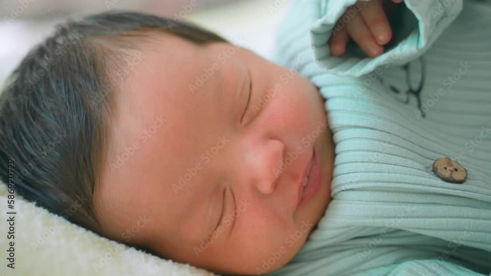 Newborn baby infant with dark hair lying on side sleeping awaking open