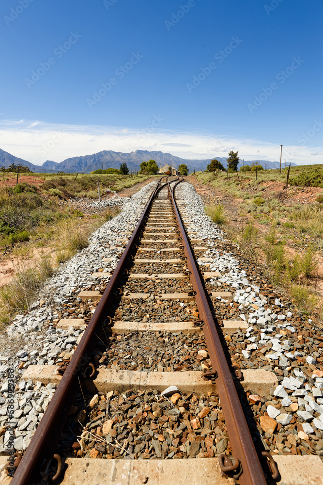 A view along railroad tracks towards high mountains in the distance, near Worcester, South Africa.