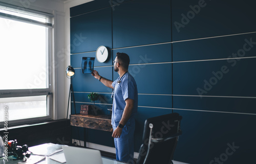 Anonymous male doctor examining x ray shot in office photo