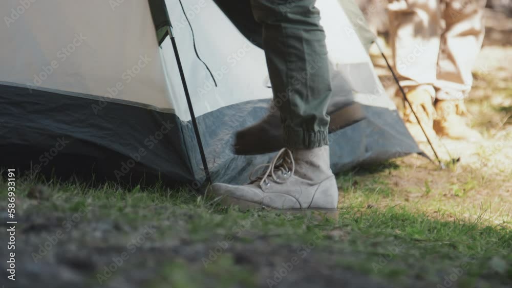 Low section of unrecognizable teen boy camping with his family staking tent to the ground Low section of unrecognizable teen boy camping with his family staking tent to the ground