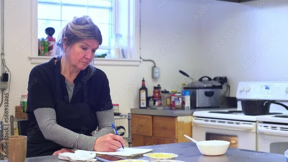 The owner of a small restaurant in her commercial kitchen working on financial issues. A concept on inflation and rising food costs. The owner of a small restaurant in her commercial kitchen working on financial issues. A concept on inflation and rising food costs.