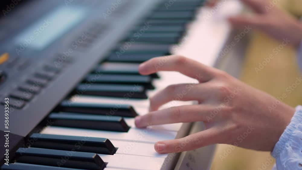 High angle view female teenage hand playing piano synthesizer keyboard in sunshine. Unrecognizable Caucasian teenager enjoying music outdoors on sunny spring summer day High angle view female teenage hand playing piano synthesizer keyboard in sunshine. Unrecognizable Caucasian teenager enjoying music outdoors on sunny spring summer day