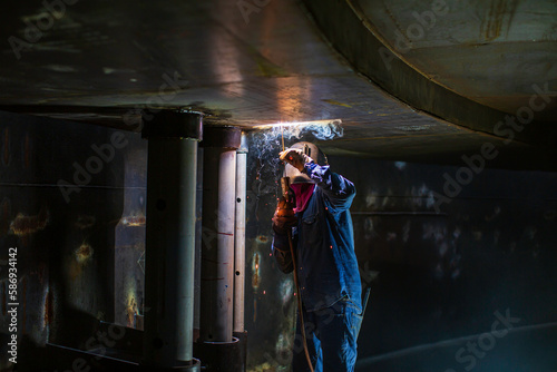 Welding male worker metal arc is part in machinery tank nozzle pipeline construction tank oil inside confined spaces. © chitsanupong