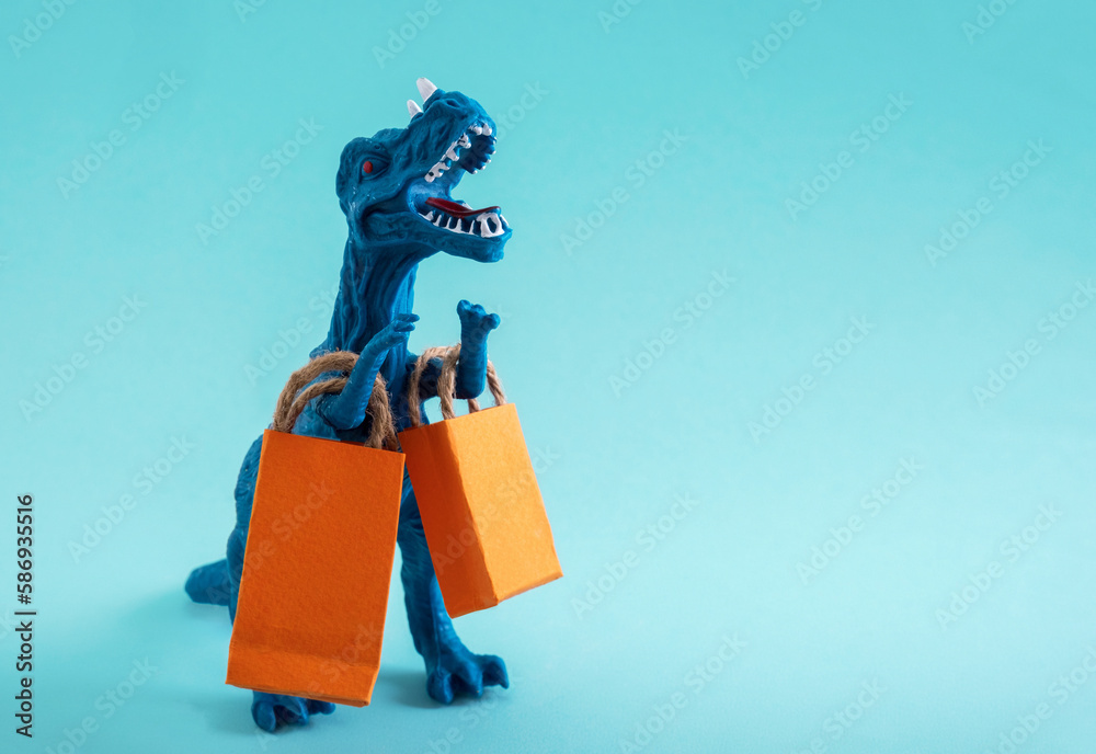 Cute blue dinosaur with orange shopping bags on a blue background. Cute humor shopping concept. Copy space. Cute blue dinosaur with orange shopping bags on a blue background. Cute humor shopping concept. Copy space.