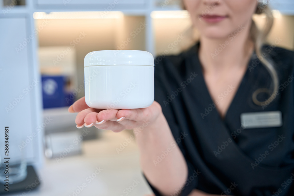 Close up photo of dermatologist showing product to camera Close up photo of dermatologist showing product to camera