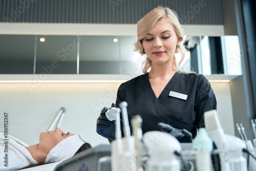 Cosmetologist preparing for skin rejuvenation therapy, working in salon photo