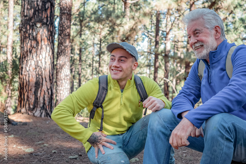 Smiling Couple of Grandfather and Young Grandson in Trekking Day Enjoying Nature and Healthy Lifestyle Together in the Woods. Adventureisageless © luciano