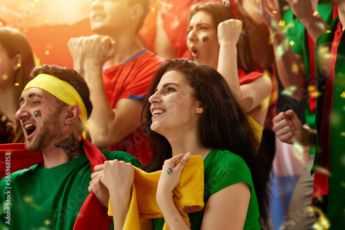 Portugal football, soccer fans cheering their team at stadium. Excited fans cheering a goal, supporting favourite players. Concept of sport, competition, championship, emotions, hobby, entertainment