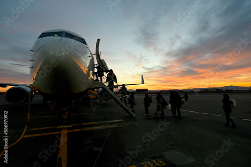 Scenic view of unrecognizable passengers silhouette boarding on airplane at sunset