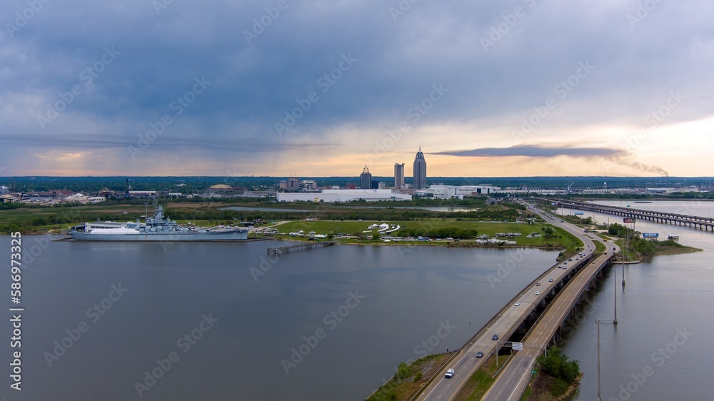 Aerial view of the USS Alabama Battleship and the downtown Mobile skyline at dusk