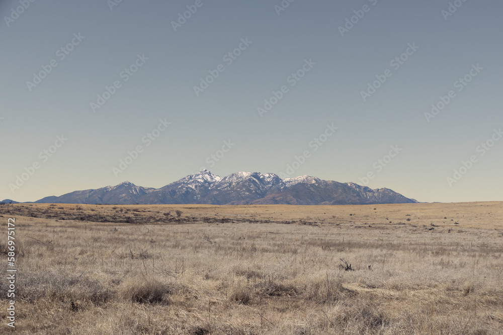 Distant mountain range with hills covered in grass in the forground in Arizona. Distant mountain range with hills covered in grass in the forground in Arizona.