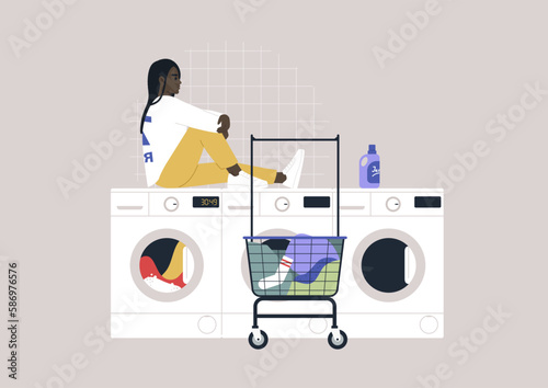 Household chores concept, a young African character waiting for their laundry in a coin laundromat