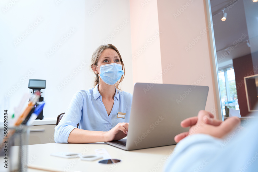 Attractive woman in protective mask is working at the laptop in the room indoors Attractive woman in protective mask is working at the laptop in the room indoors