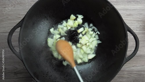 White onion cubes falling on the hot frying vok and mixing photo