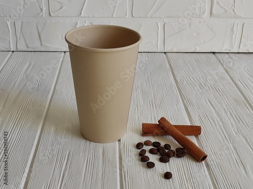 disposable paper cup, coffee beans, cinnamon sticks on white background