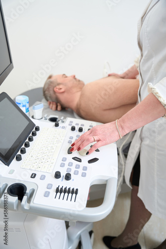 Male patient undergoing examination chest by doctor with ultrasonography device