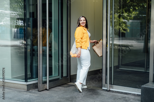 Plus size Wellbeing, Ways to Practice Body Positivity. focus on self-love and acceptance. Happy confident curvy young woman in yellow cloth walking on city street