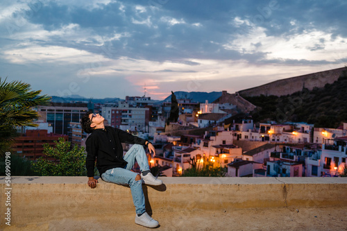 Young transgender man looking up while posing outdoors at sunset.