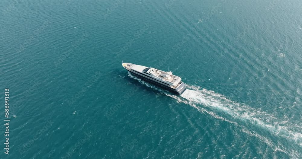 White luxury motor yacht sailing with water scooter blue sea surface with small waves in sea aerial view drone. Tourists strolling boat. White path on water boat. White luxury motor yacht sailing with water scooter blue sea surface with small waves in sea aerial view drone. Tourists strolling boat. White path on water boat.