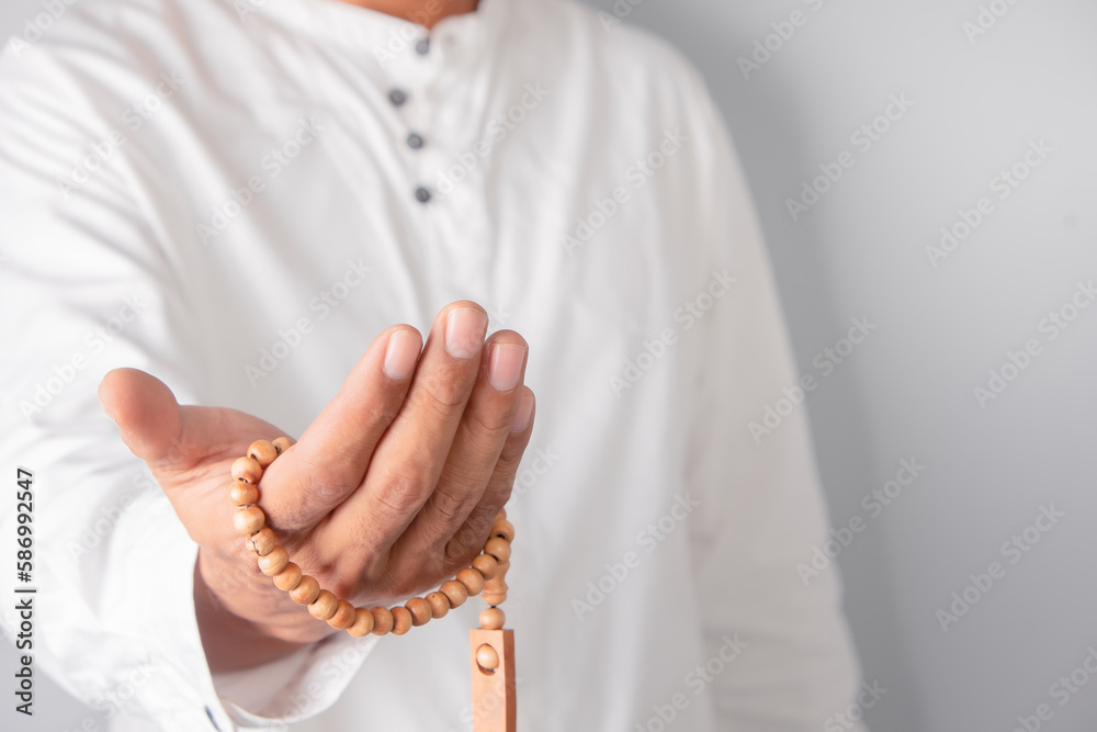 Hand of a Muslim man holding tasbih beads