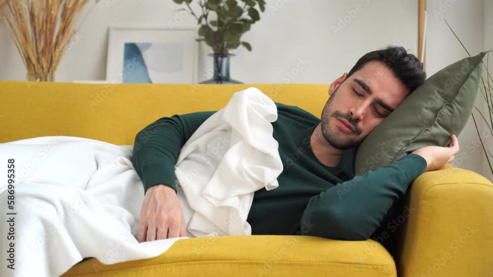 Young man lying on sofa and sleeping in cozy living room at home