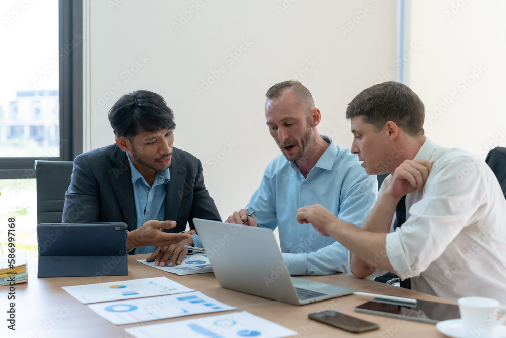Group of diverse businessman going over paperwork together and working on laptop at meeting. Group of diverse businessman going over paperwork together and working on laptop at meeting.