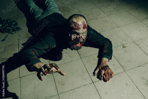 Fotografie Zombie male creeps on floor halloween concept